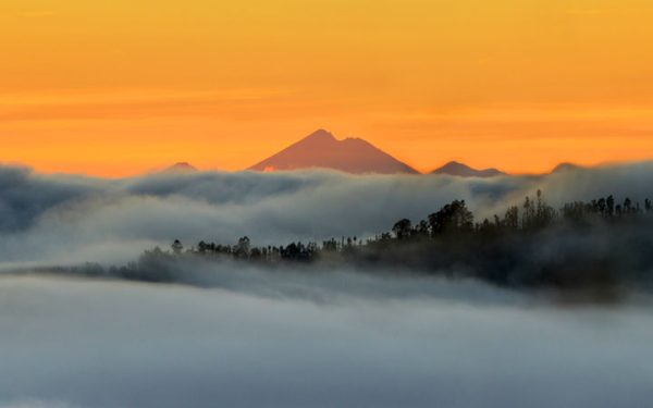Kabut tebal, pemandangan gunung, plus langit oranye bikin suasana makin dramatis. Photo by Koes nadi.