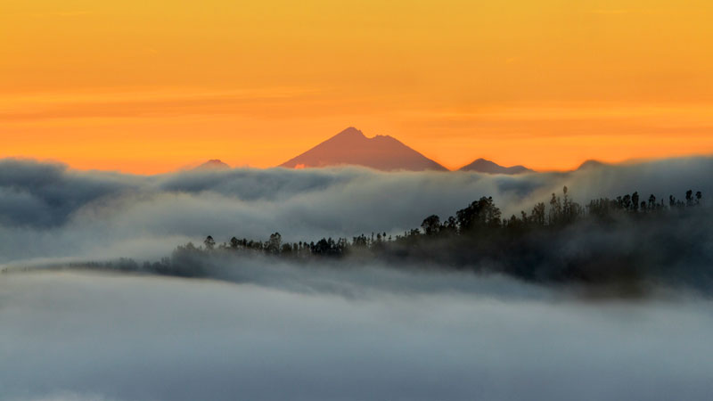 Kabut tebal, pemandangan gunung, plus langit oranye bikin suasana makin dramatis. Photo by Koes nadi.