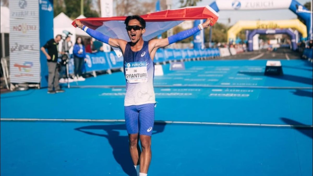 Robi Syianturi, pelari terbaik Asia Tenggara di marathon Asian Games 2026, berselebrasi dengan bendera Indonesia