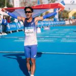 Robi Syianturi, pelari terbaik Asia Tenggara di marathon Asian Games 2026, berselebrasi dengan bendera Indonesia