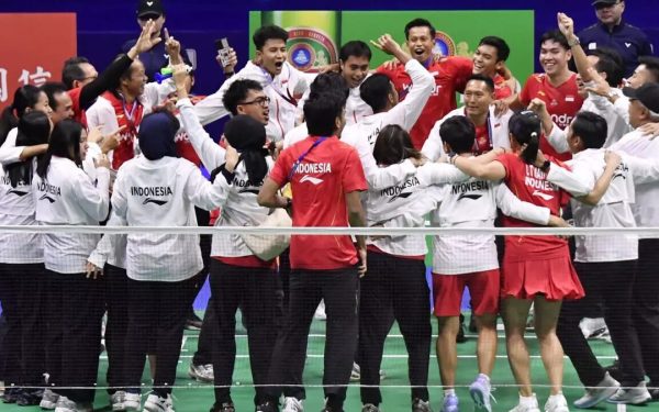 Tim bulu tangkis Indonesia selebrasi bersama di sisi net dengan jaket Indonesia