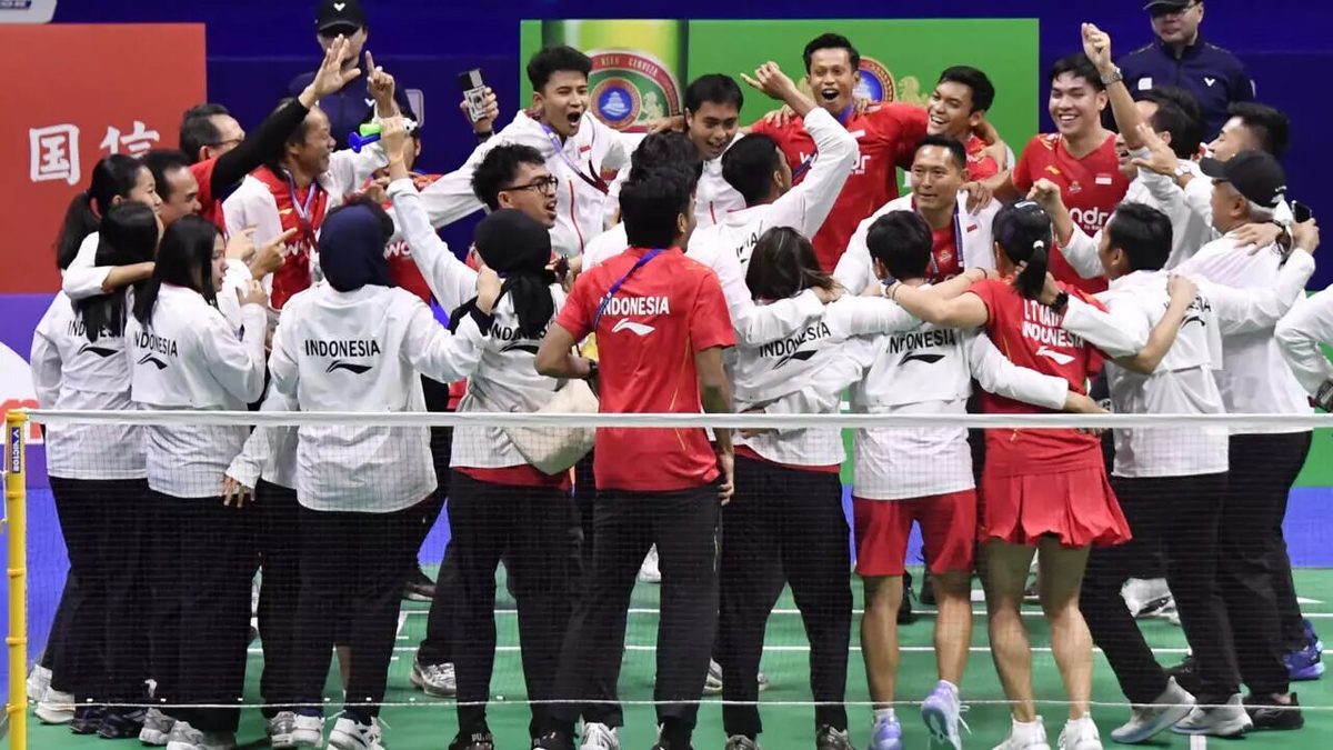 Tim bulu tangkis Indonesia selebrasi bersama di sisi net dengan jaket Indonesia