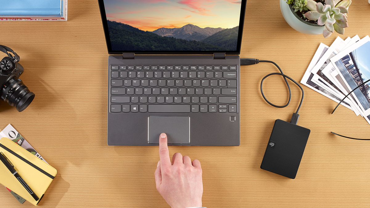 Laptop dan hard disk eksternal di atas meja kerja