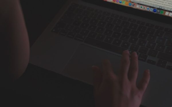 Tangan mengetik di laptop dalam ruangan redup