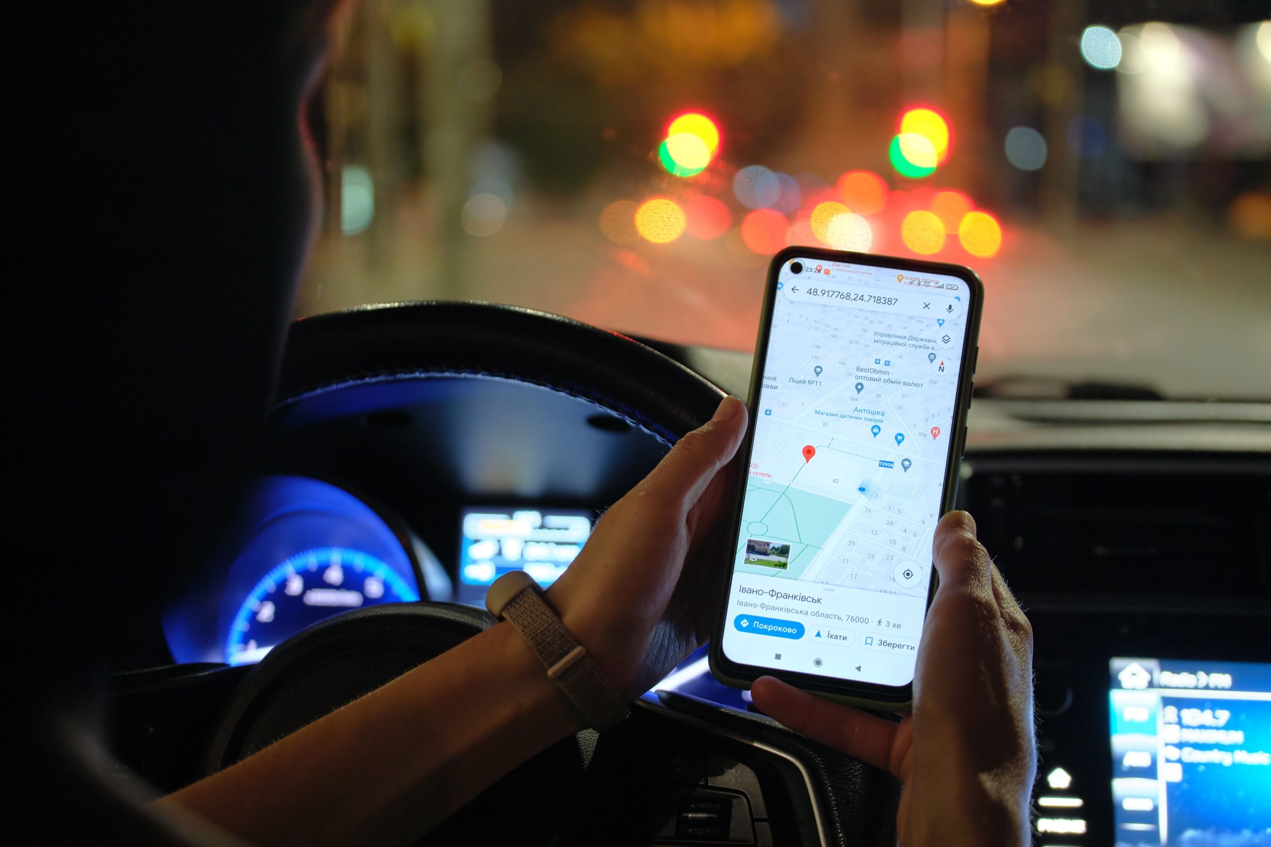 Pengemudi memegang ponsel dengan peta di dalam mobil