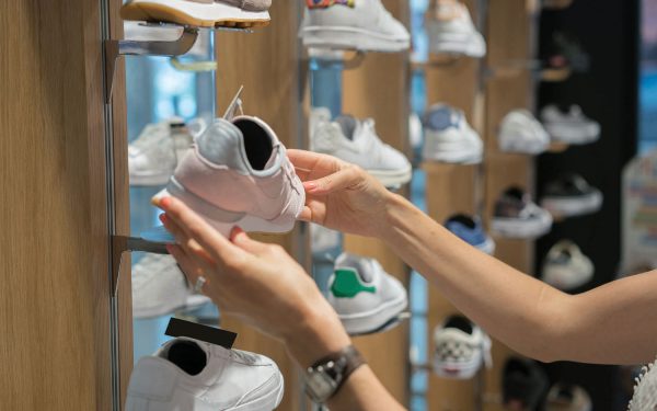 Seseorang memegang sepatu olahraga di dalam toko