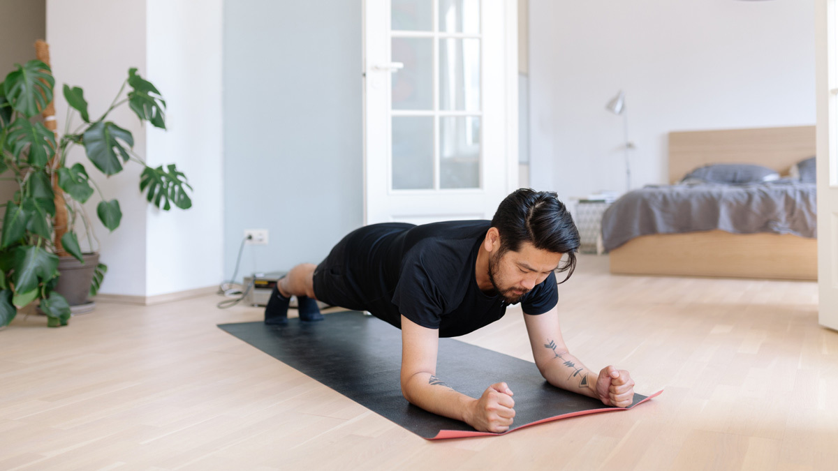 Seseorang berlatih push-up di lantai kayu