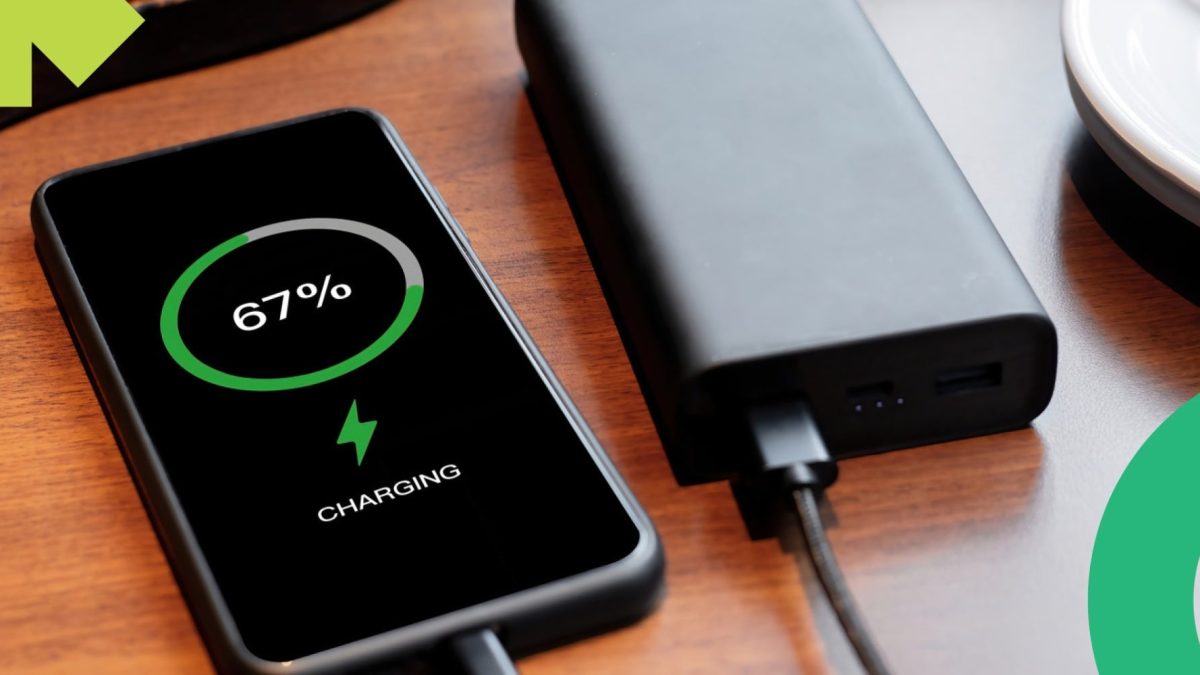 Ponsel diisi daya dari power bank hitam di atas meja kayu