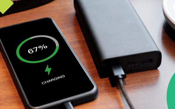 Ponsel diisi daya dari power bank hitam di atas meja kayu