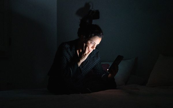 Wanita menggunakan ponsel di ruangan gelap dengan layar menyala