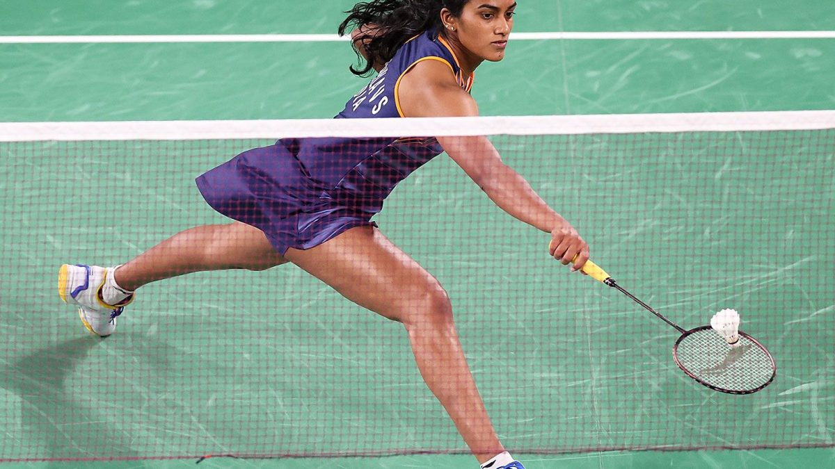 Atlet bulu tangkis memukul smash di lapangan indoor