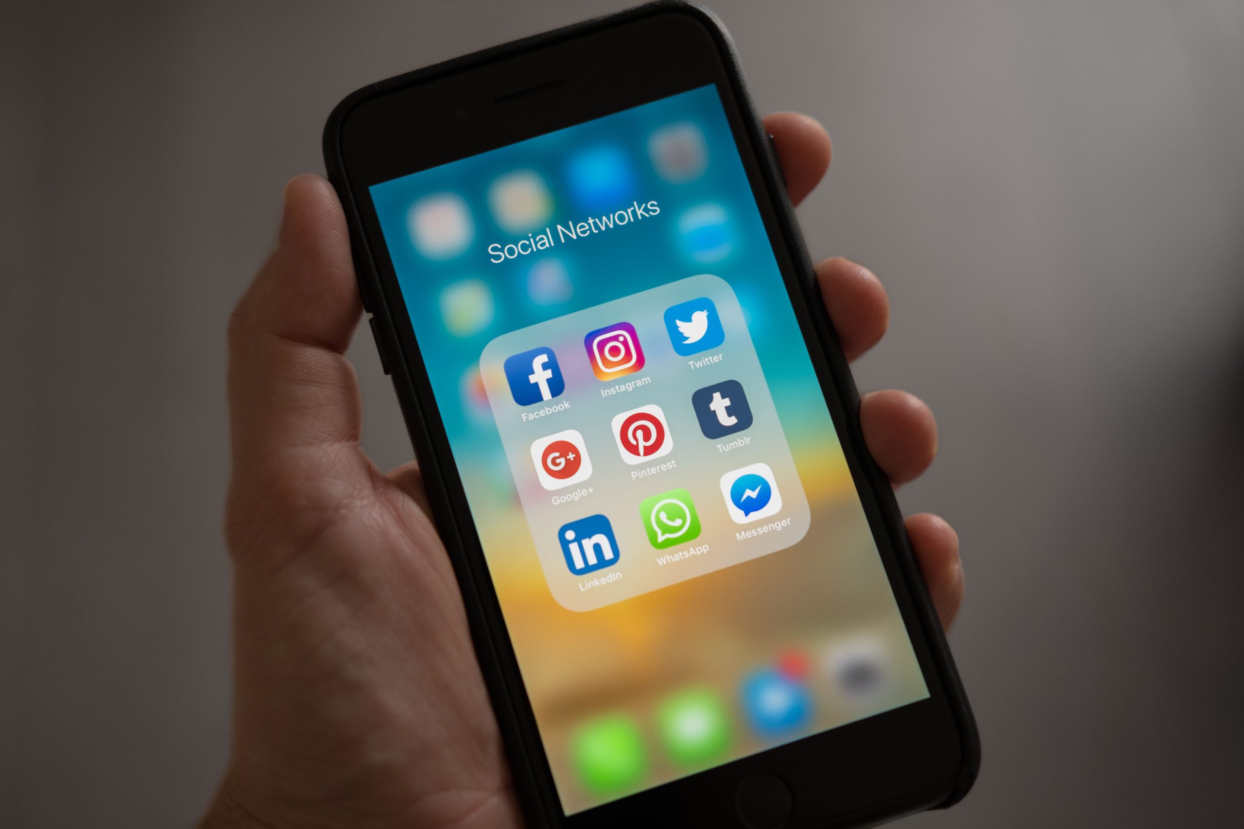 Ponsel di tangan dengan folder aplikasi terbuka
