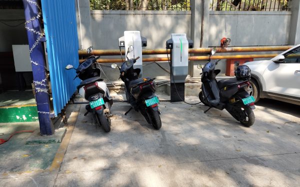 Tiga motor listrik terparkir mengisi daya di stasiun pengisian luar ruangan