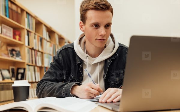 Mahasiswa bekerja dengan laptop di perpustakaan