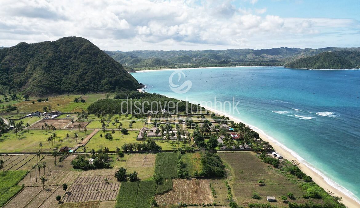 Pemandangan udara garis pantai Lombok dengan laut biru kehijauan dan perbukitan