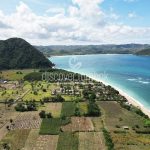 Pemandangan udara garis pantai Lombok dengan laut biru kehijauan dan perbukitan