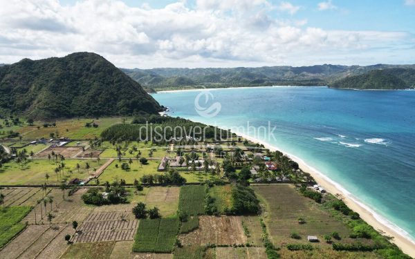 Pemandangan udara garis pantai Lombok dengan laut biru kehijauan dan perbukitan