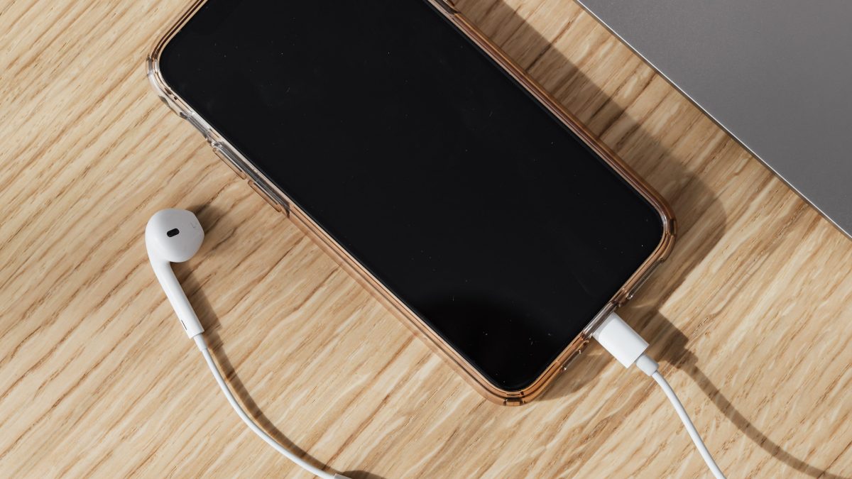 Kabel, ponsel, dan laptop di atas meja kayu