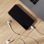 Kabel, ponsel, dan laptop di atas meja kayu
