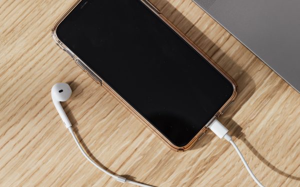 Kabel, ponsel, dan laptop di atas meja kayu